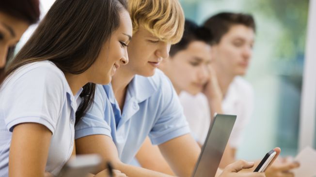 Two high school students looking at a lapton and a phone