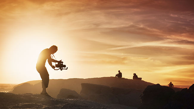 Man holding camera and drone at dusk on some rocks
