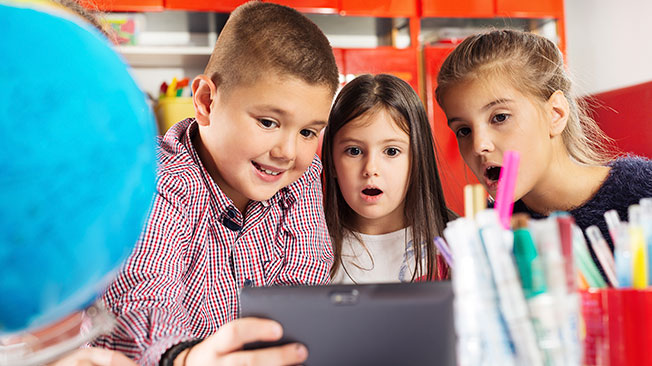 Three children looking at a hand-held screen in awe