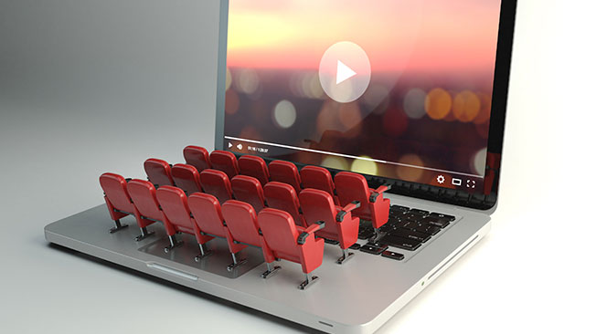 laptop computer with video on screen and cinema style seating popping up from keyboard