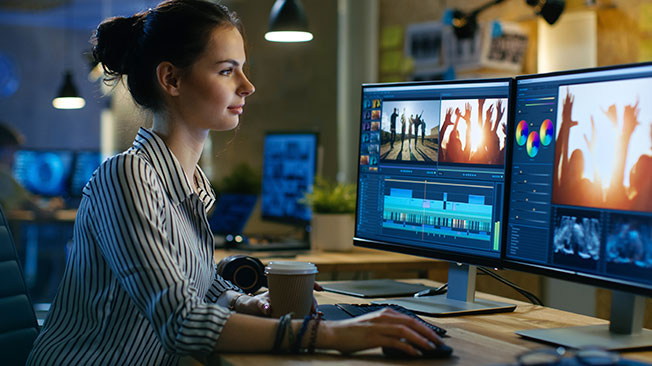 Picture of woman in front of two-screen set-up and editing software on screen