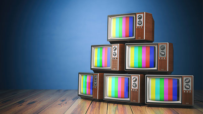 Stack of vintage televisions with colour bars on screen